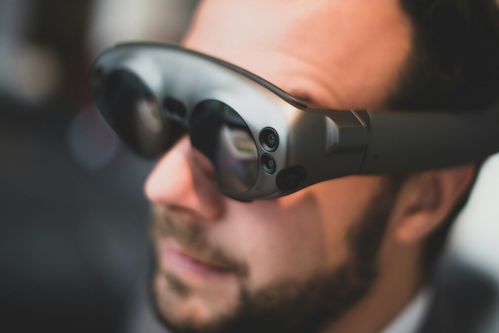 A person wearing futuristic AR-style glasses against a neutral grey background