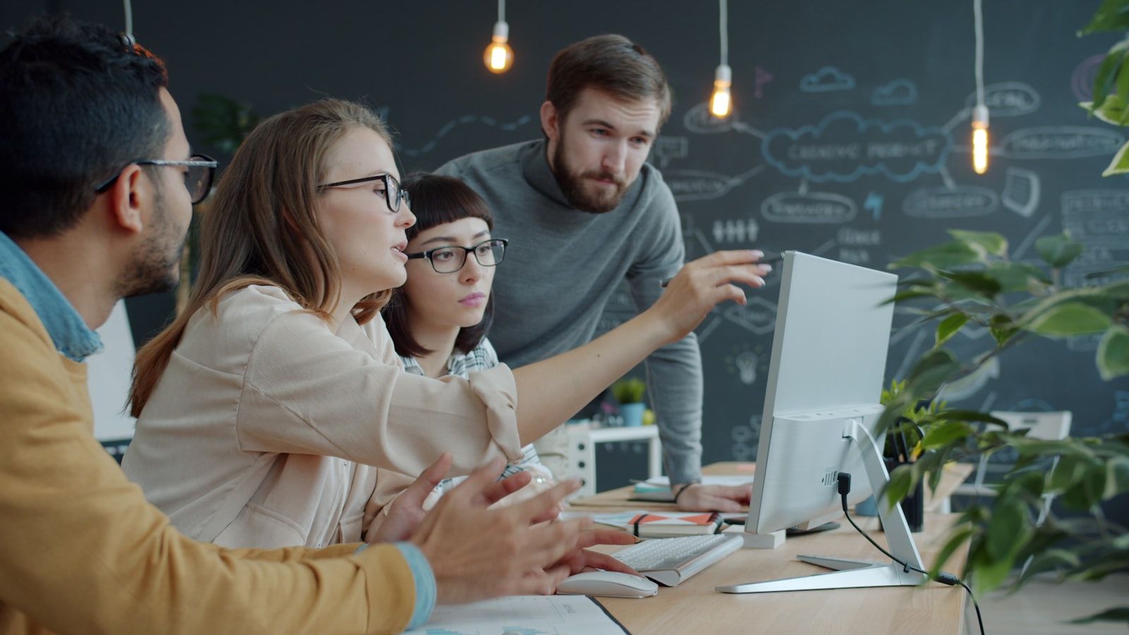 Colleagues in an open office laughing and pointing at a shared laptop screen